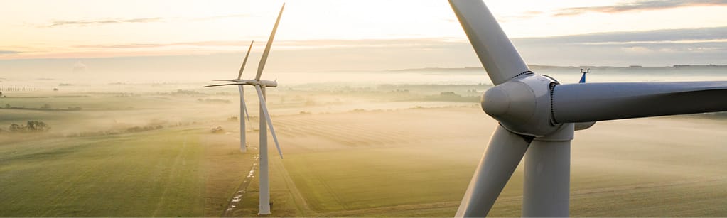 Aerial view of three wind turbines in the early morning fog at sunrise in the English countryside